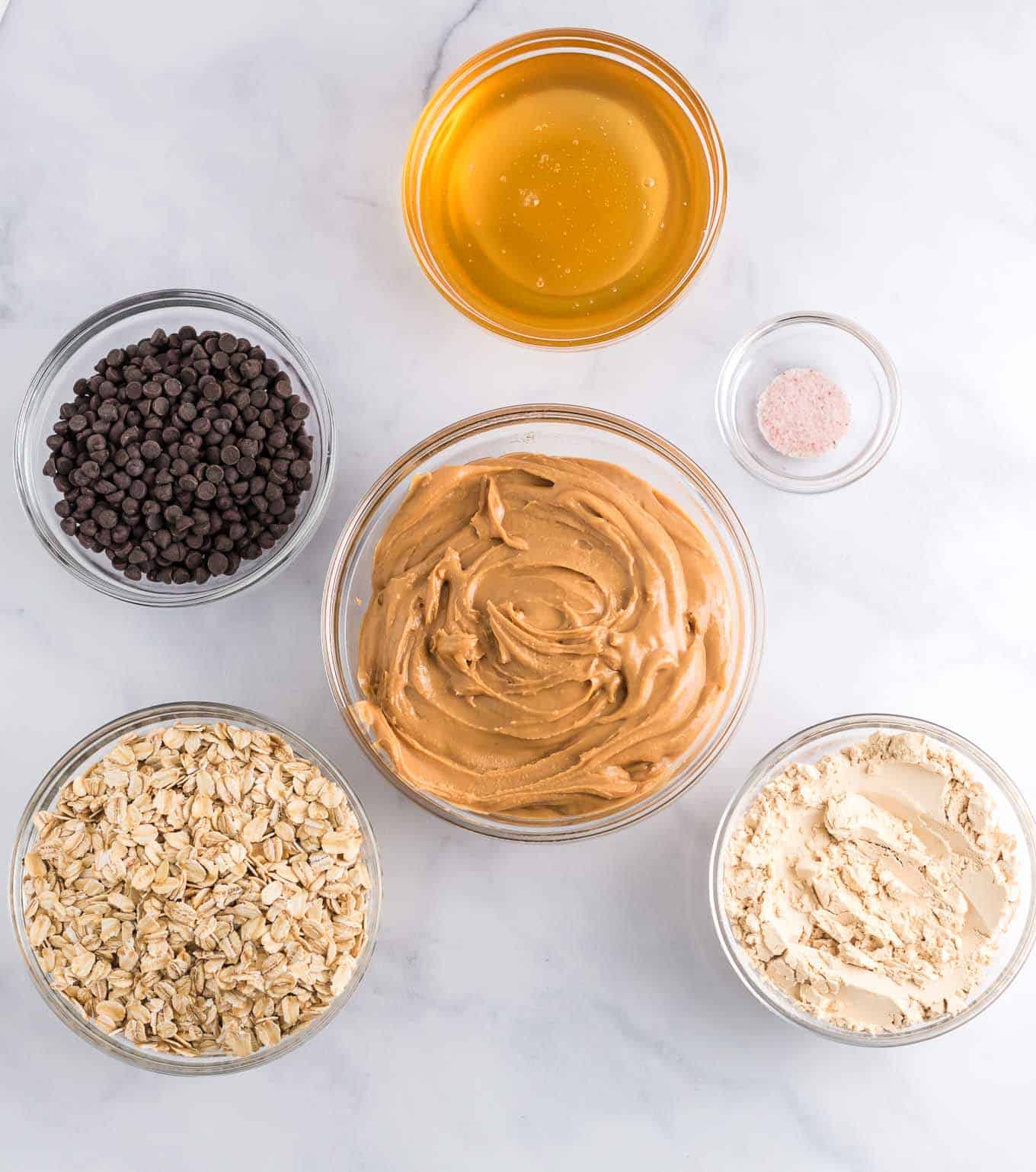 ingredients overhead picture - peanut butter, protein powder, salt, oats, honey, and mini chocolate chips