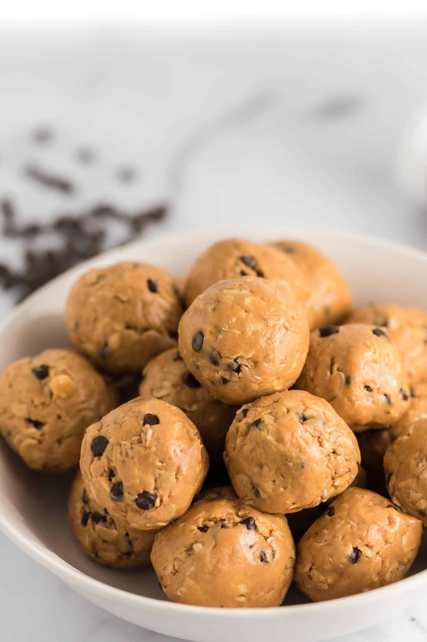 energy balls in a bowl from the side with chocolate chips in the background