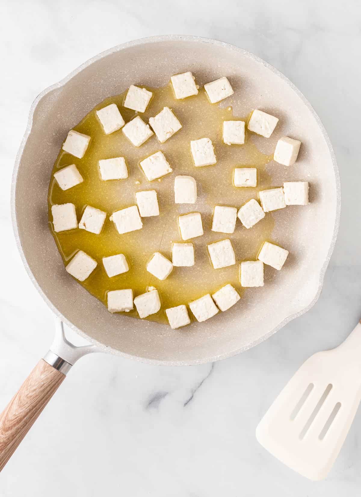 adding the tofu to the skillet with oil