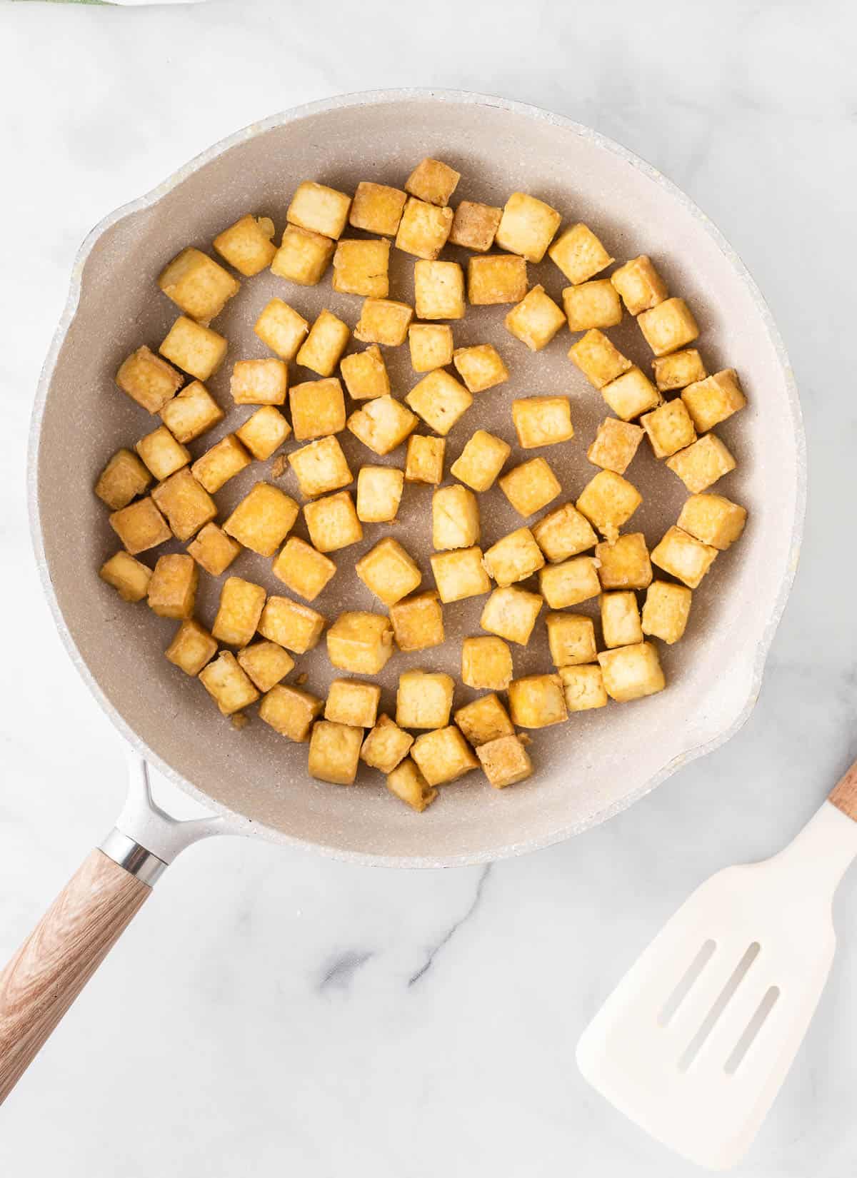 crispy golden tofu cubes in the skillet