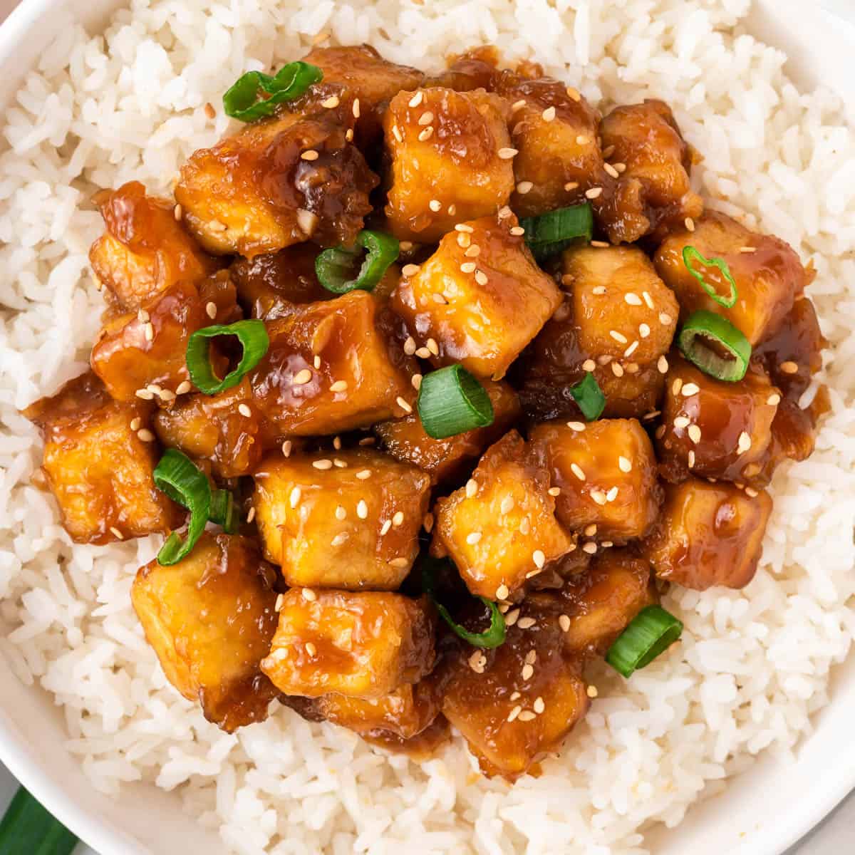 orange tofu over rice in a bowl