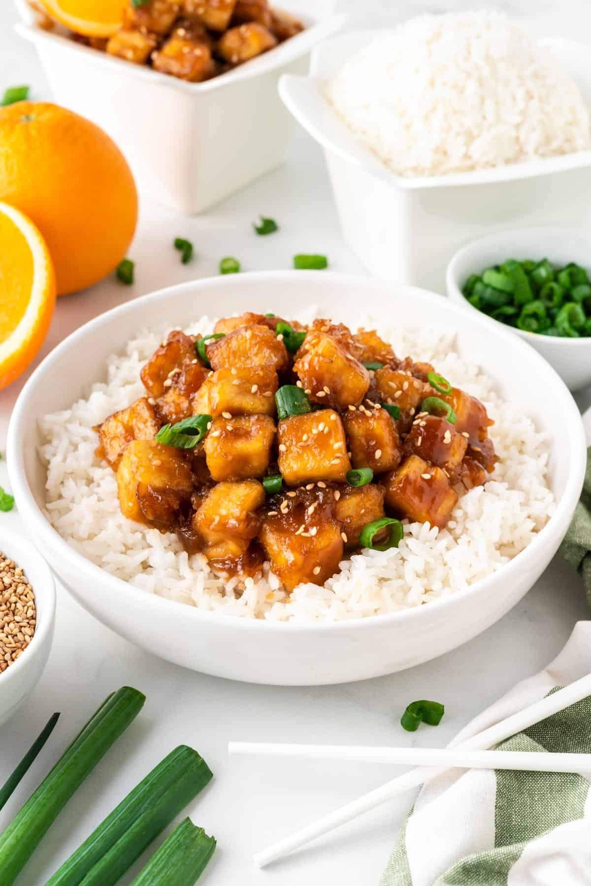 orange tofu over rice in a bowl
