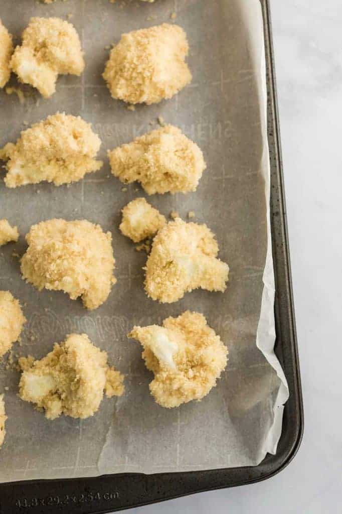breaded cauliflower bites on a parchment paper lined baking sheet