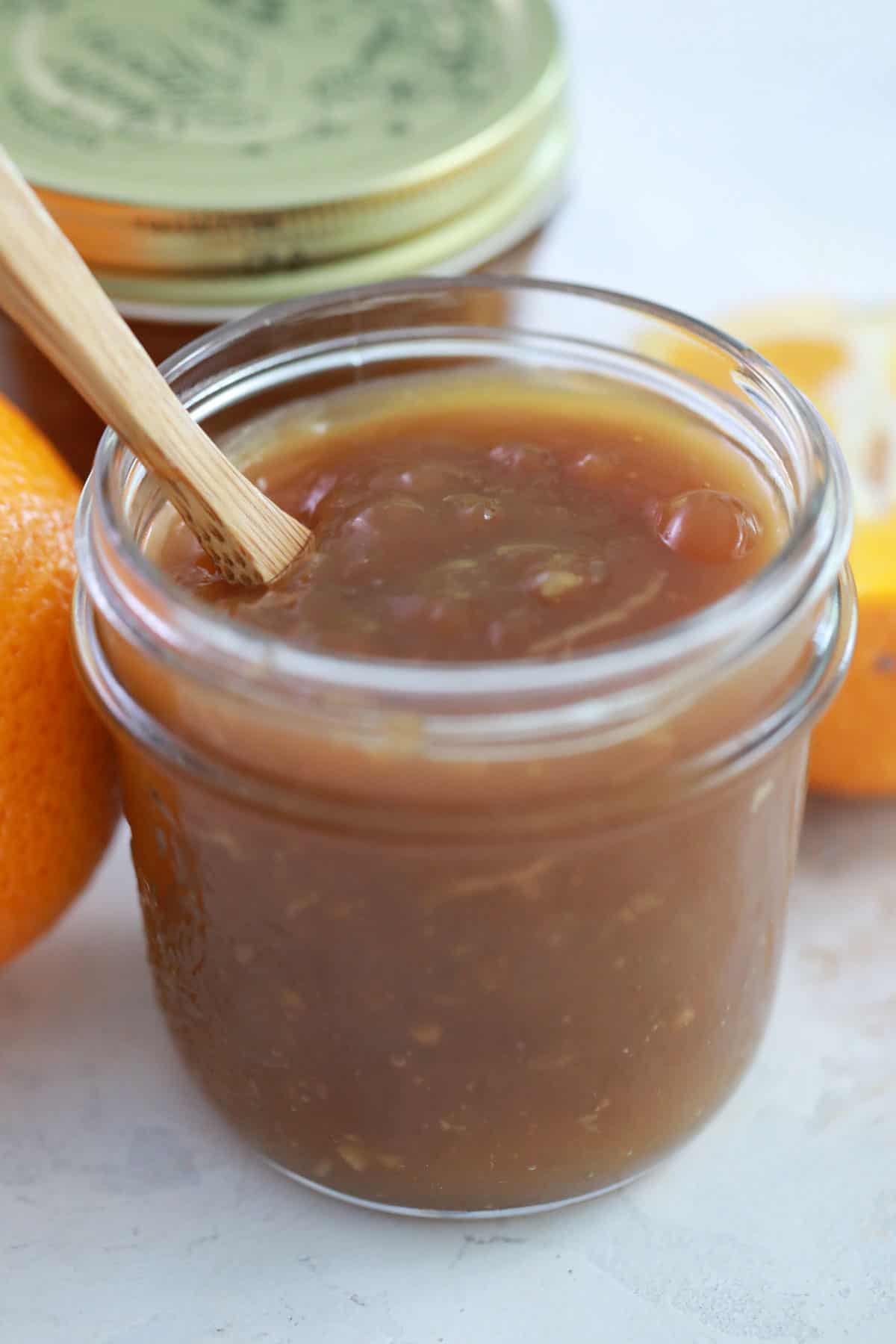 a jar full of orange sauce with a wooden spoon in it