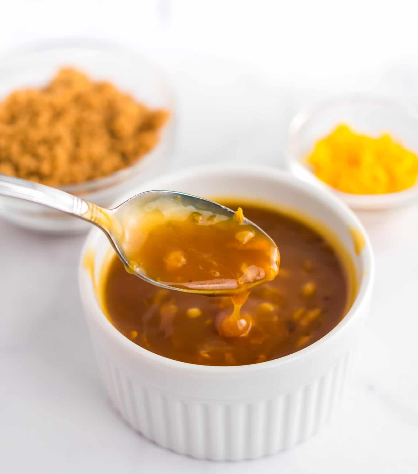 a spoon dipping into orange sauce