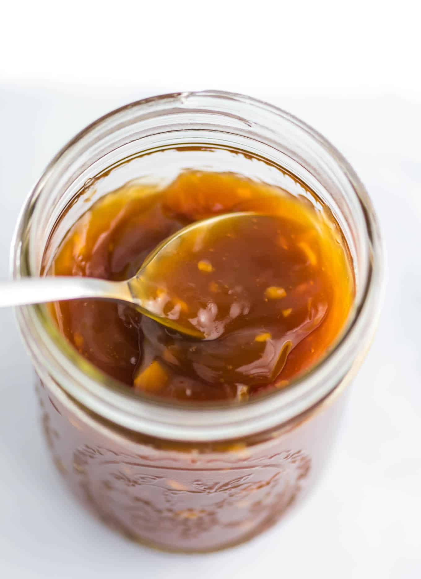 spoon inside a mason jar of orange sauce
