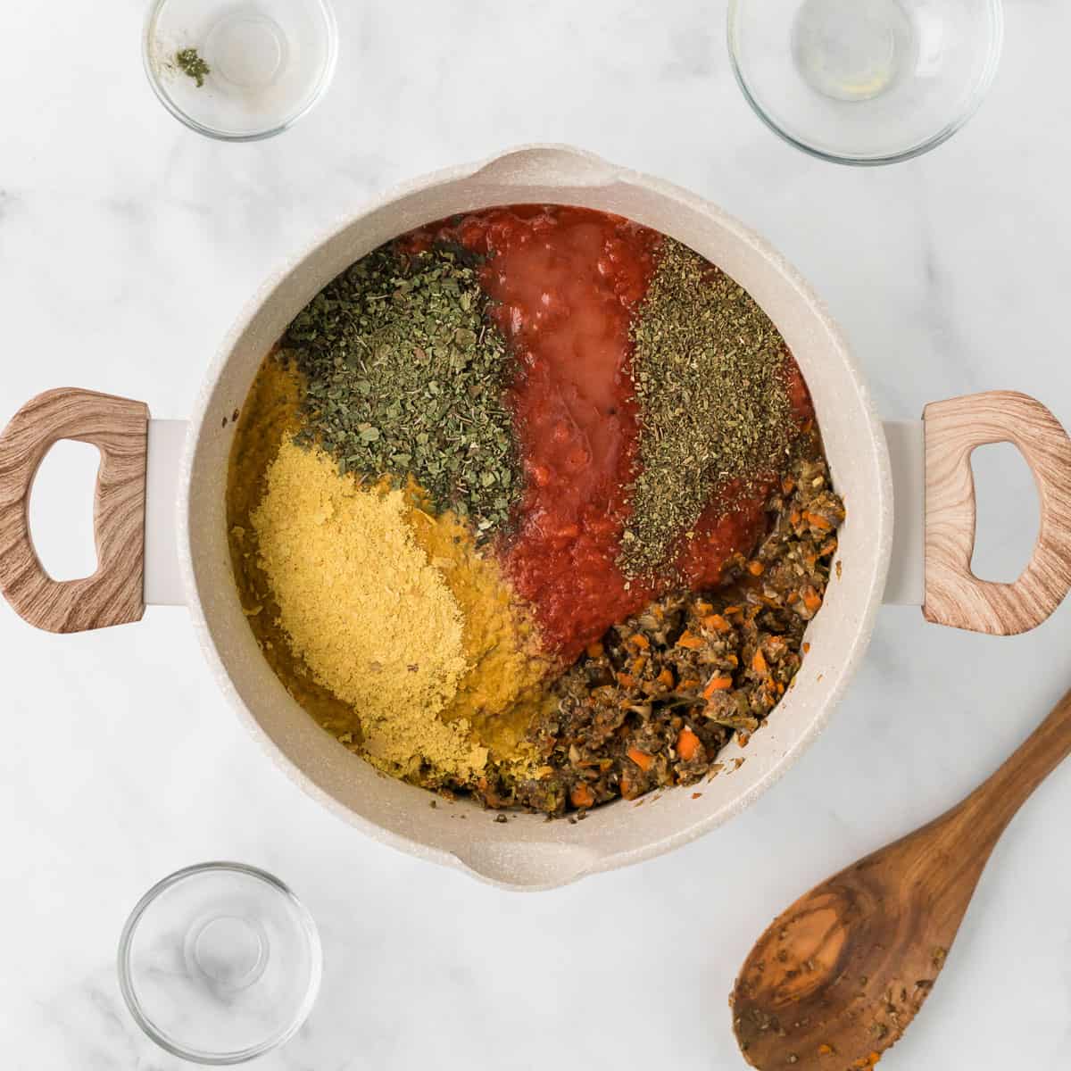 adding the nutritional yeast, tomatoes, and spices to the vegetarian bolognese