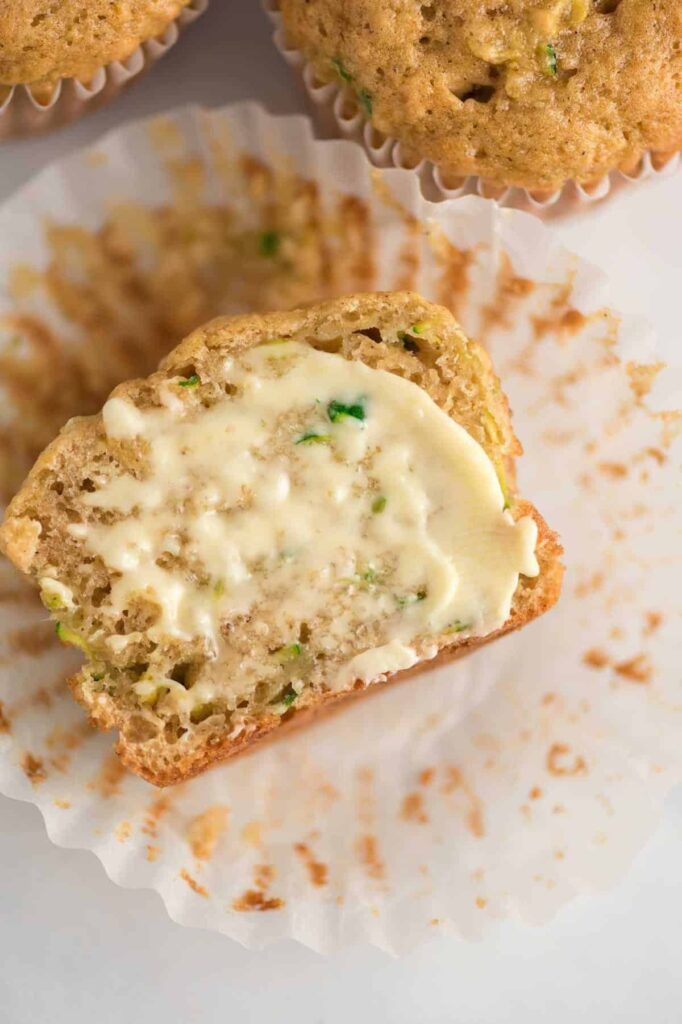 zucchini muffin cut in half with butter smeared on it