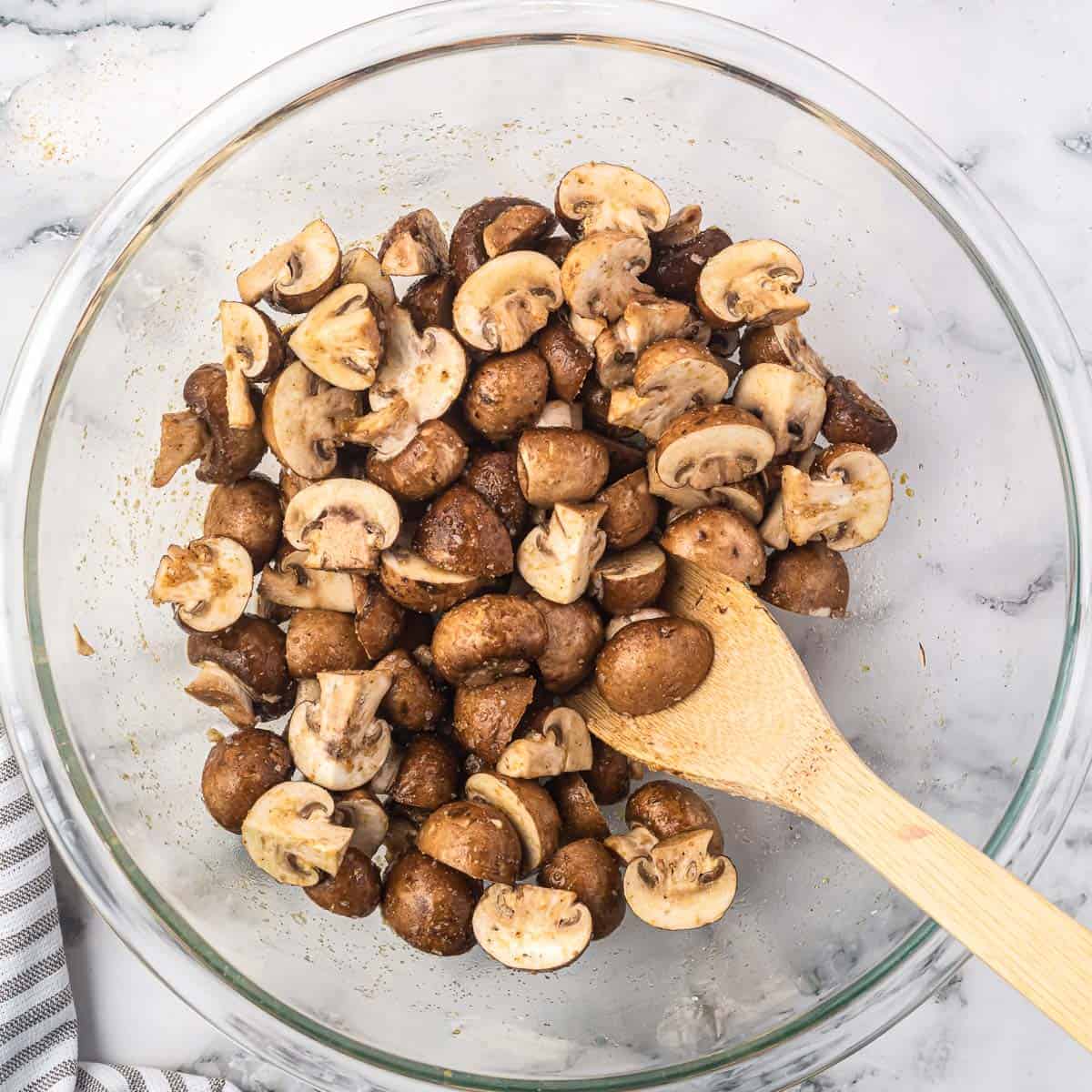 cut mushrooms in a bowl mixed together with the oil and spices