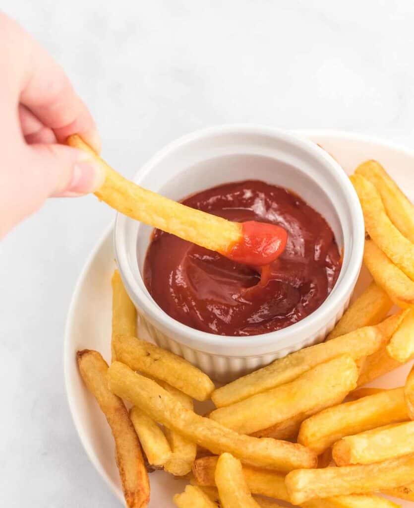 a french fry being dipped in ketchup