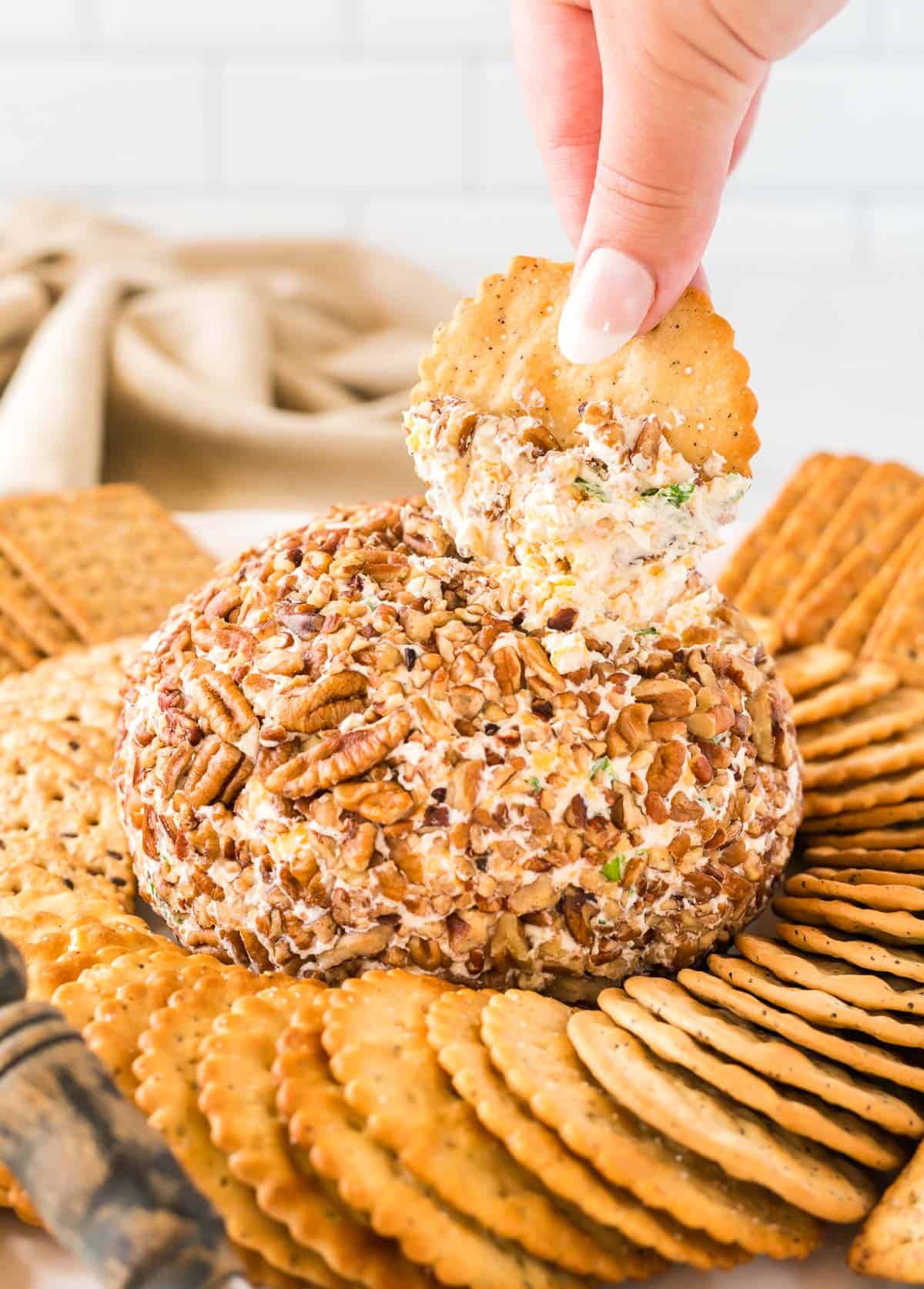 holding a cracker dipped in cheese ball