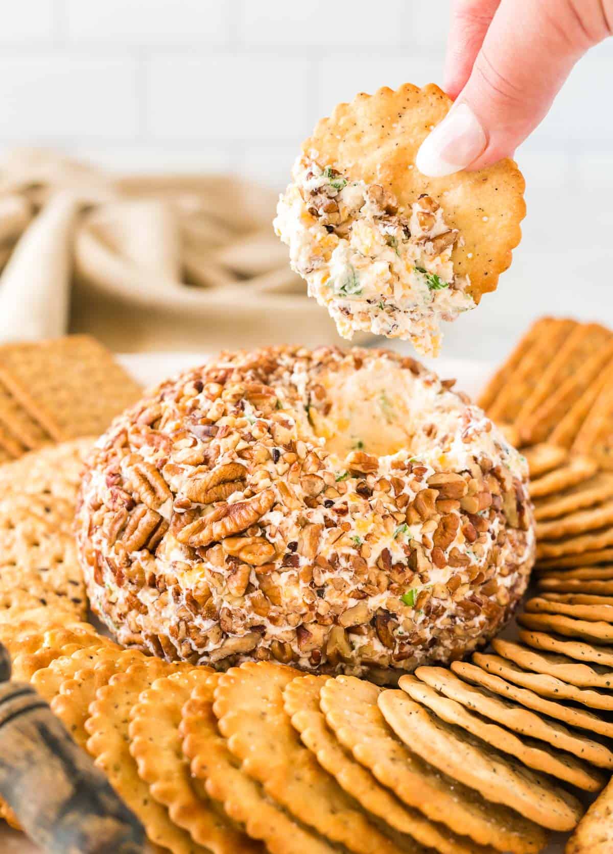 holding a cracker dipped in cheese ball