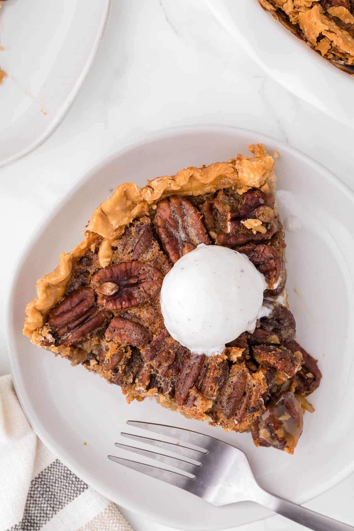 slice of maple pecan pie topped with a scoop of ice cream