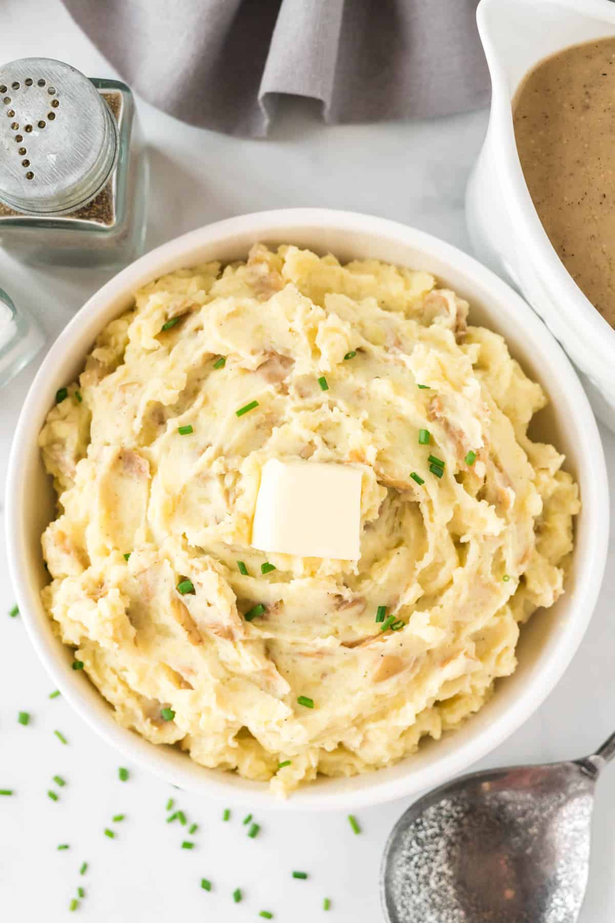 mashed potatoes in a bowl topped with butter and chives