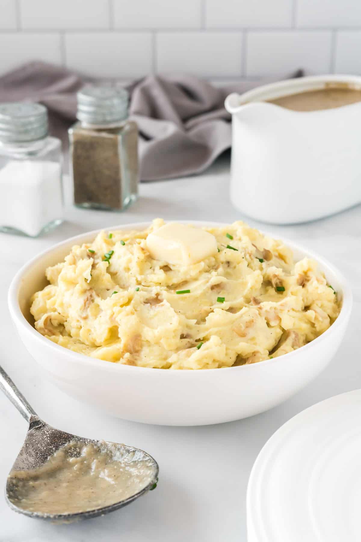 mashed potatoes in a bowl topped with butter and chives