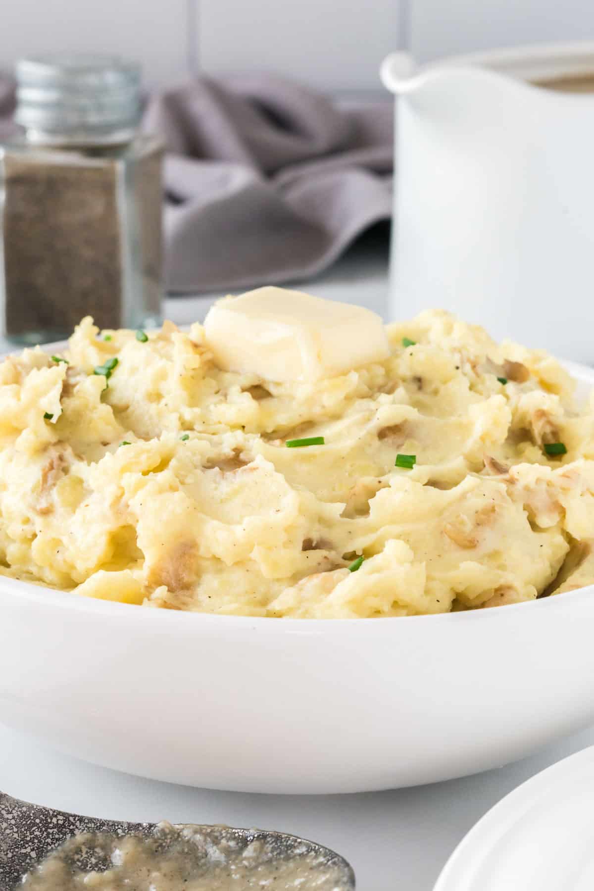 mashed potatoes in a bowl topped with butter and chives