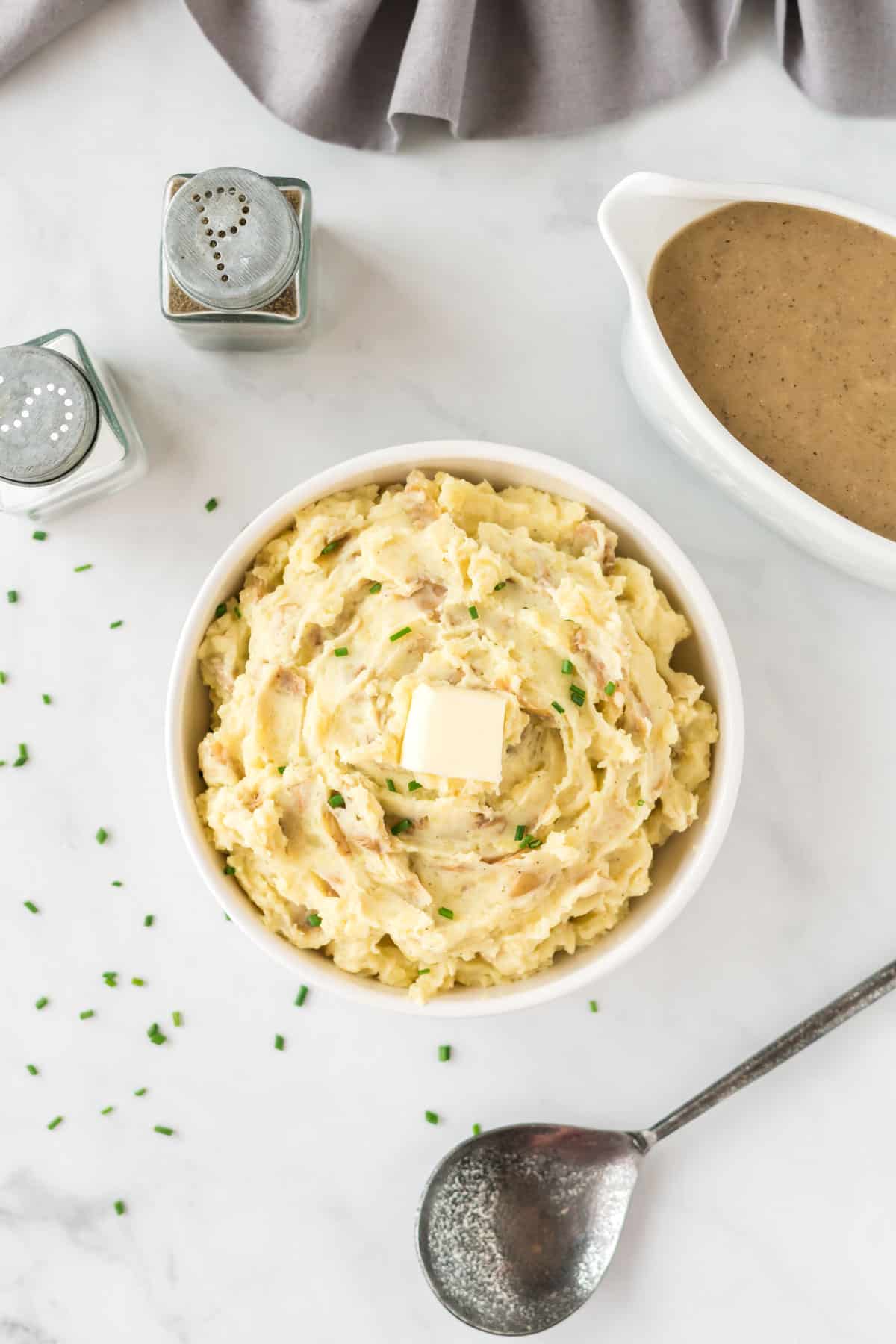 mashed potatoes in a bowl topped with butter and chives