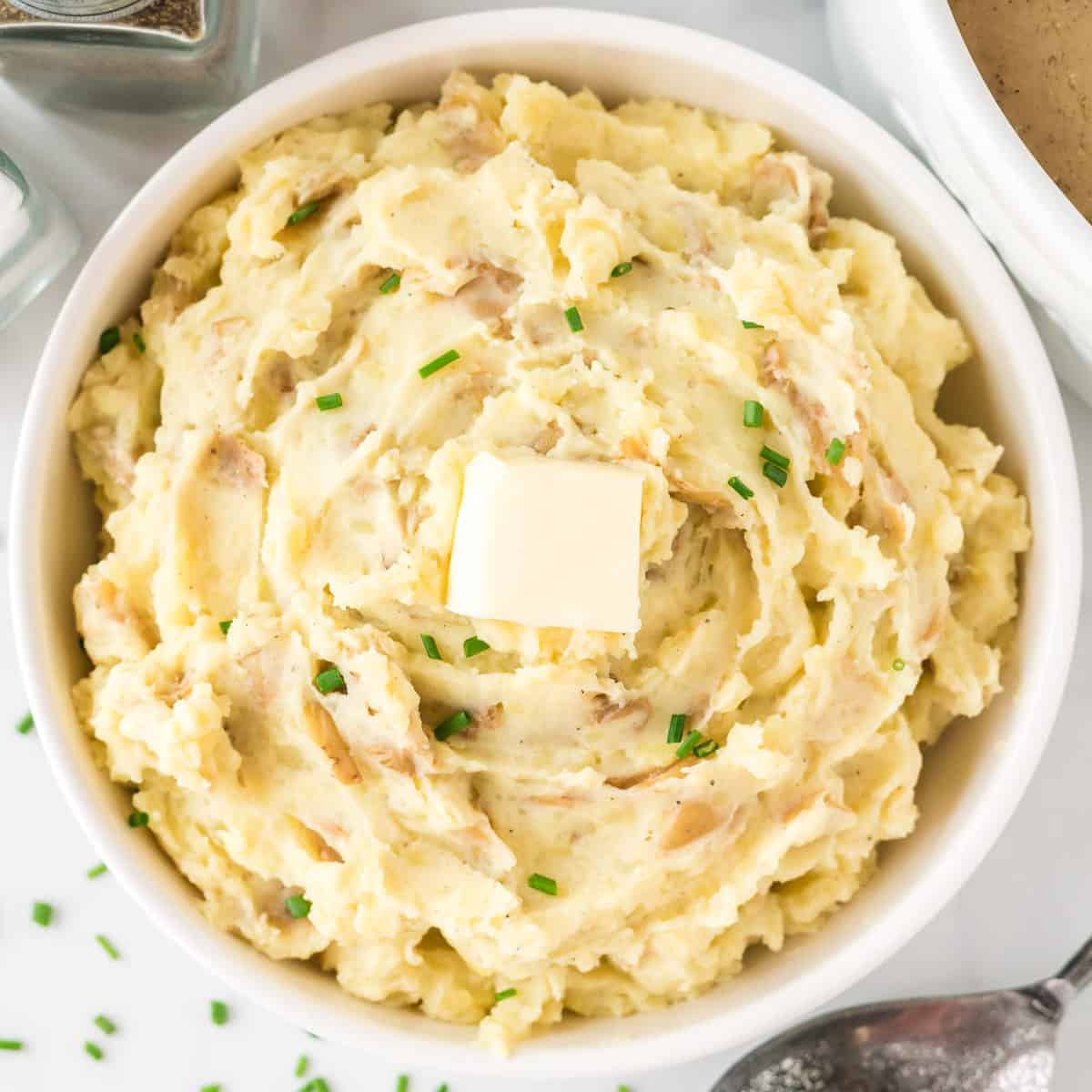 mashed potatoes in a bowl topped with butter and chives