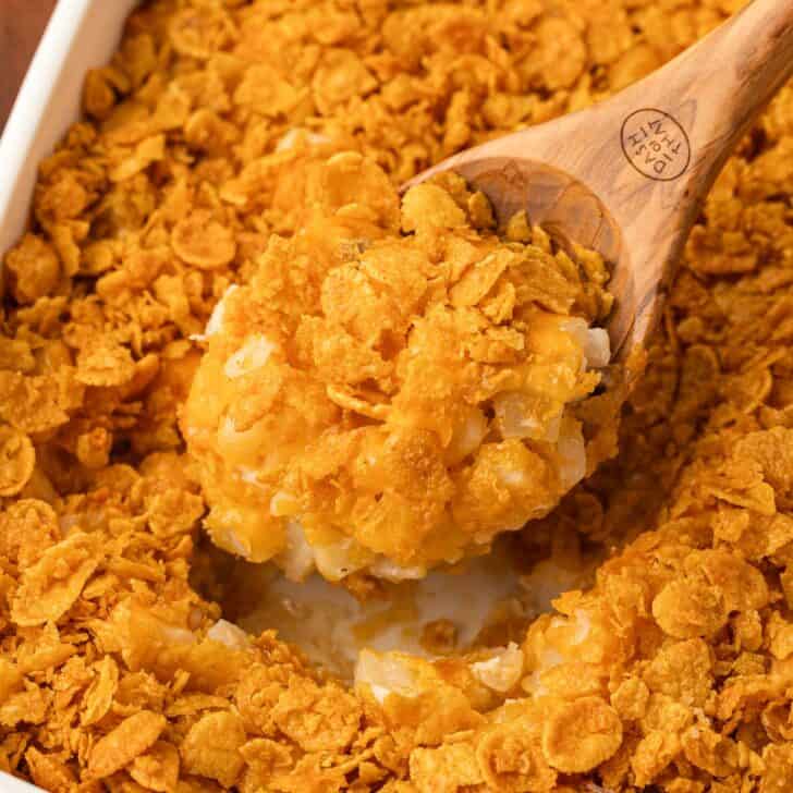 taking a scoop of funeral potatoes from the baking dish