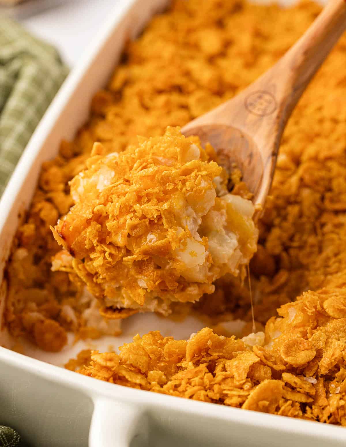 taking a scoop of funeral potatoes from the baking dish