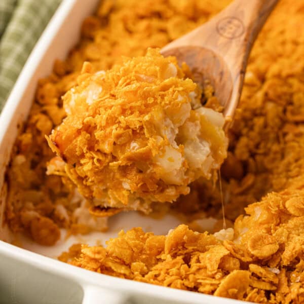 taking a scoop of funeral potatoes from the baking dish