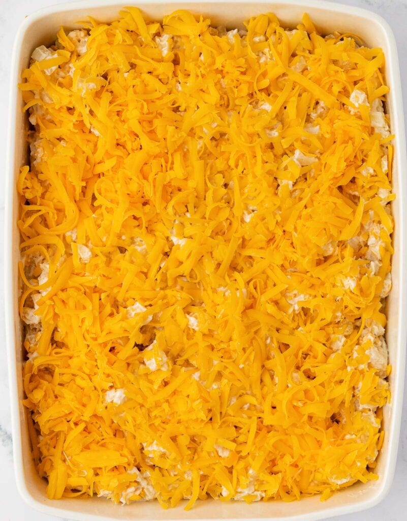 cheesy hash brown potatoes in a baking dish topped with cheddar cheese