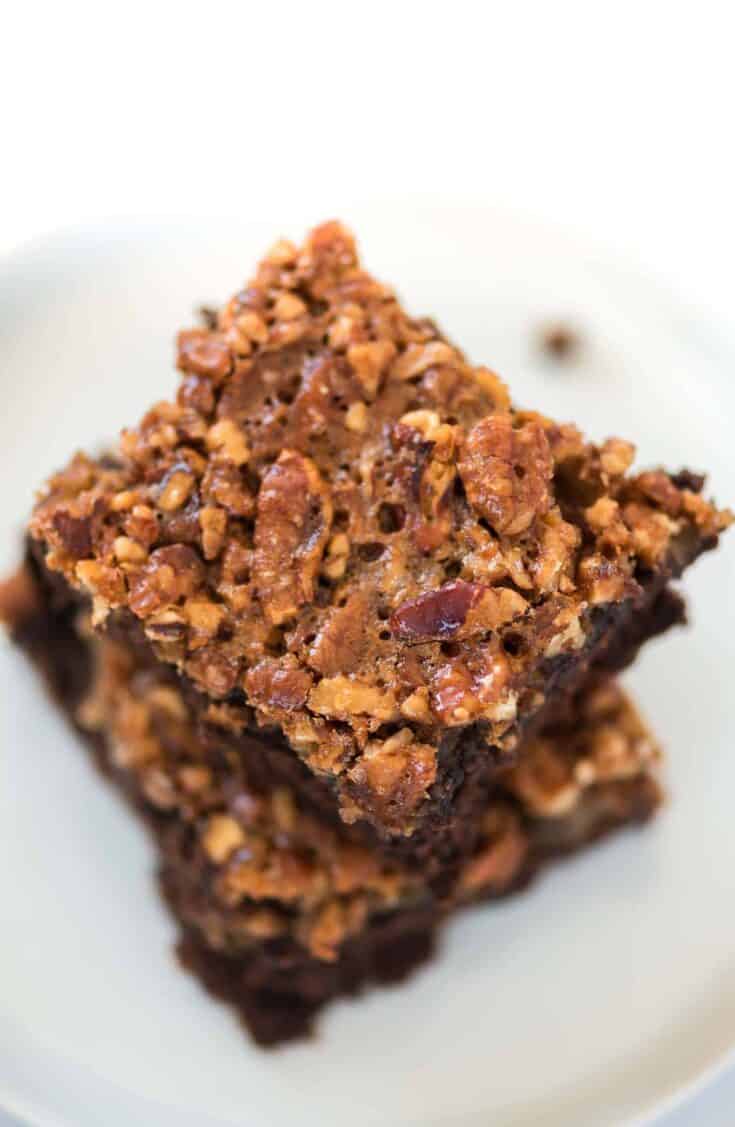 two pecan brownies stacked on a white plate