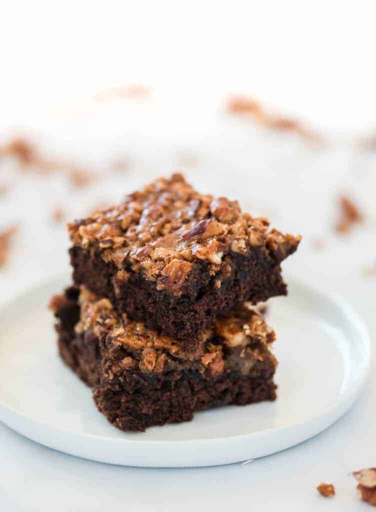 two pecan brownies stacked on a white plate