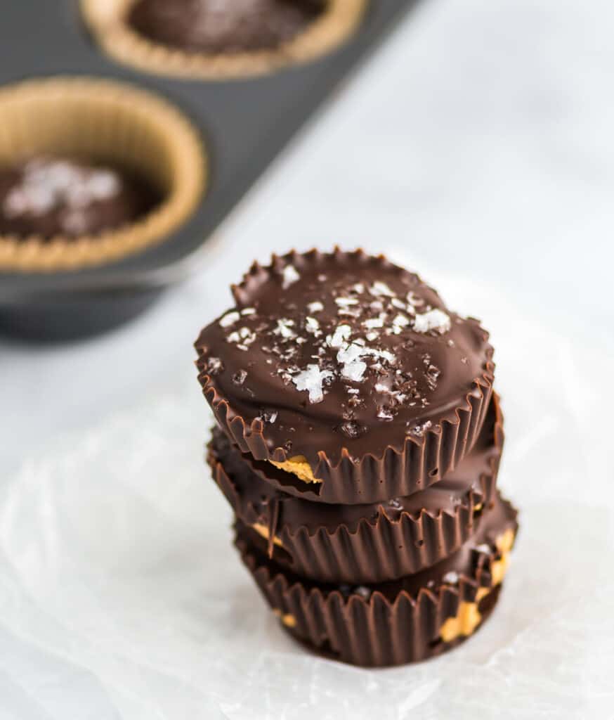 three peanut butter cups stacked with a muffin tin in the background