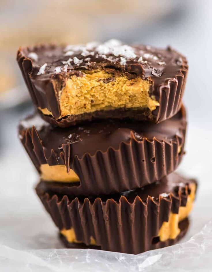 three protein peanut butter cups stacked with the top one taken a bite out of to show the filling