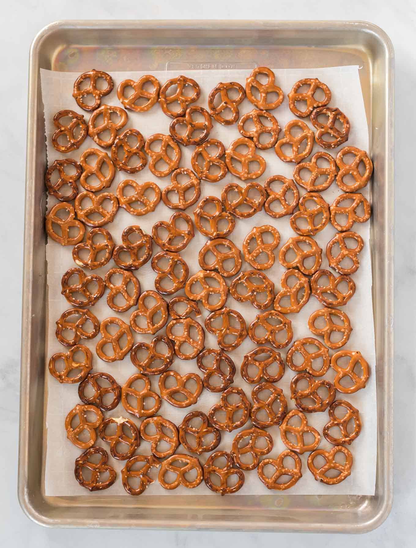 a baking sheet lined with parchment paper with pretzels covering it