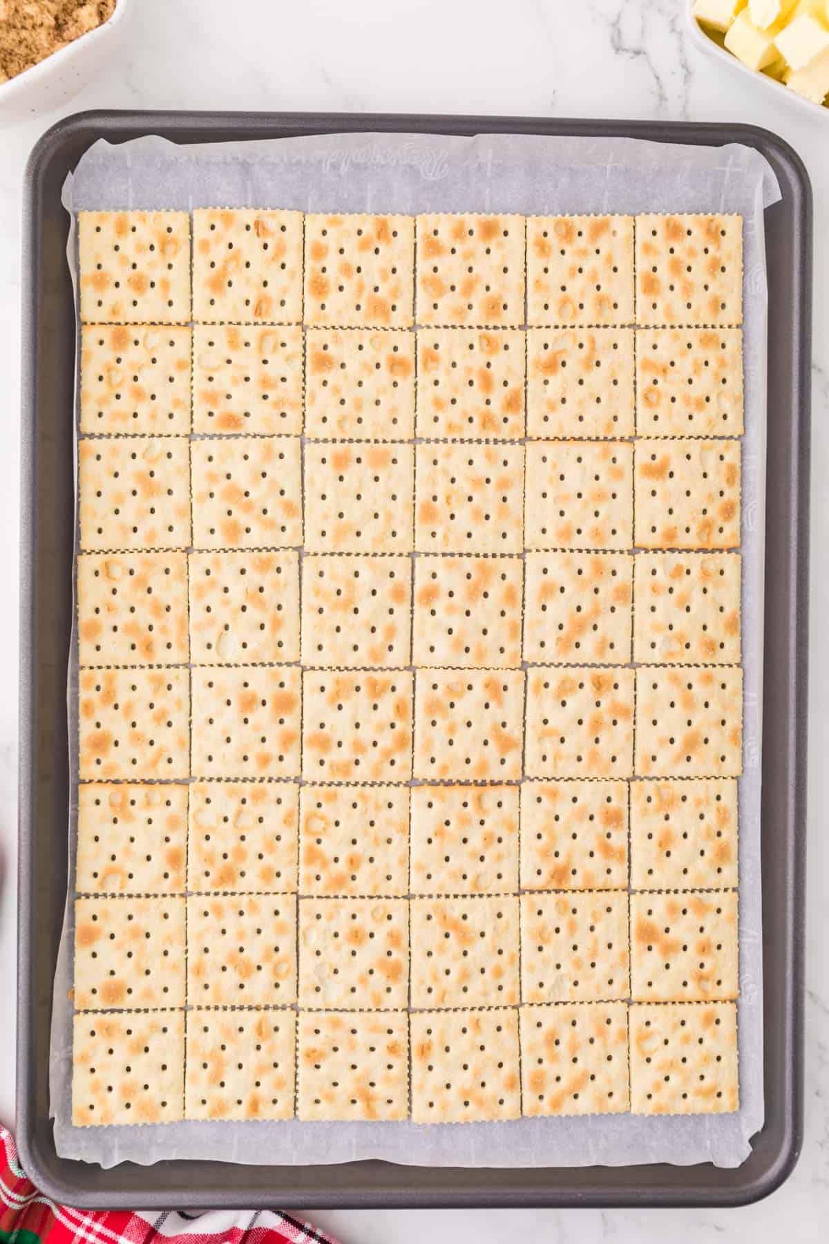 saltine crackers lined on a baking sheet