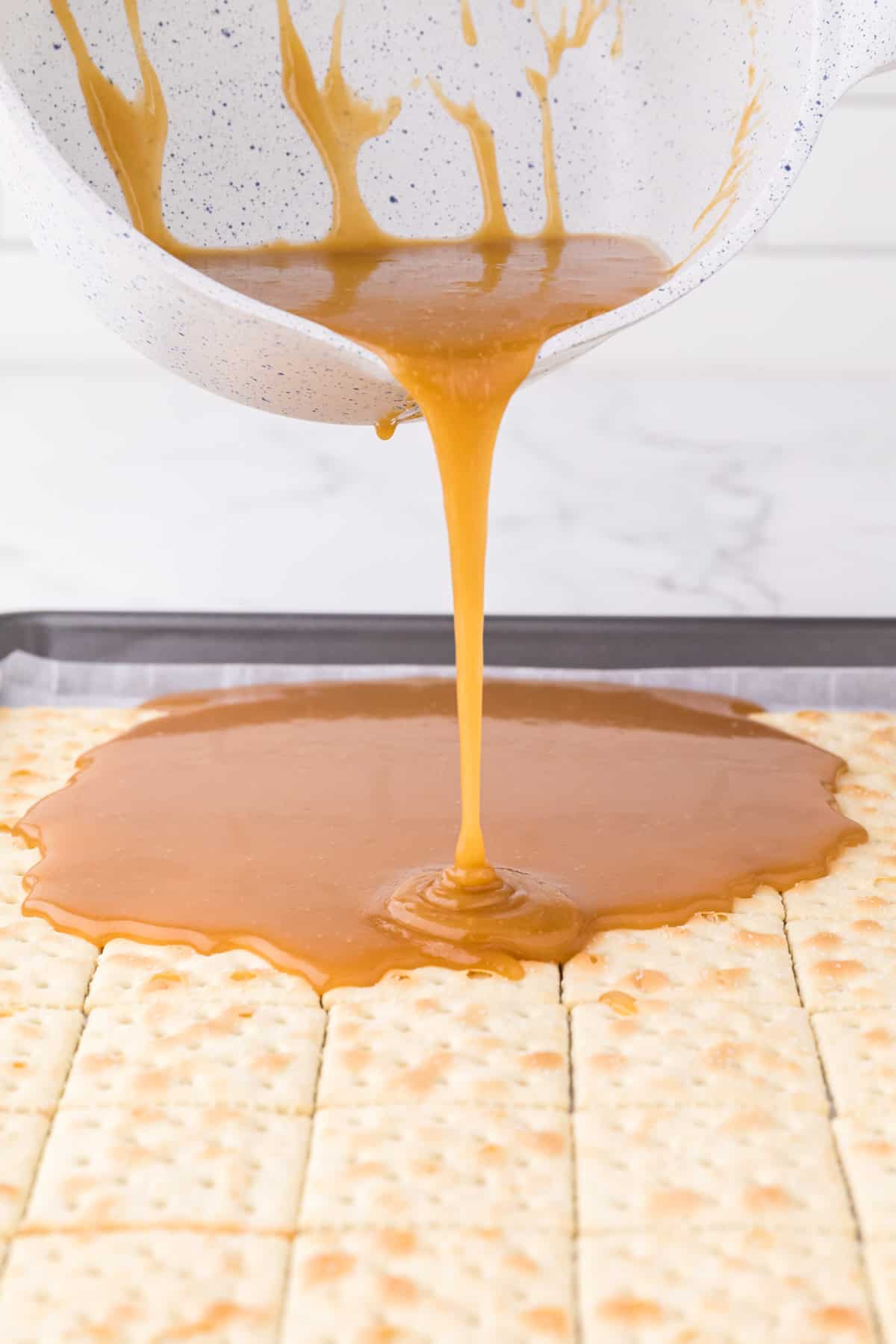pouring the toffee layer over the saltines