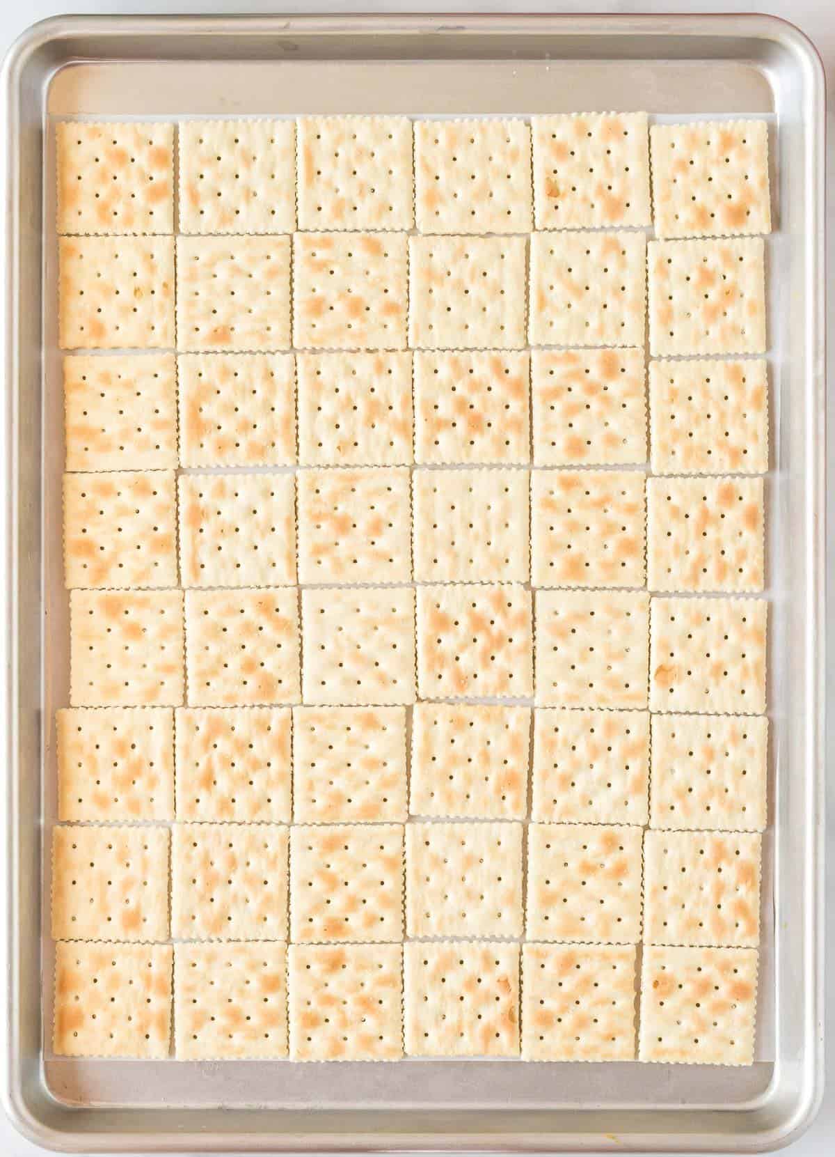 saltines lined up on a baking sheet