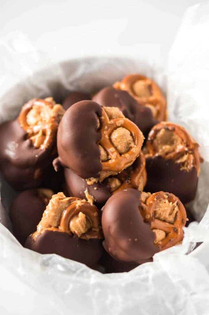 chocolate dipped peanut butter pretzels in a wax paper lined bowl
