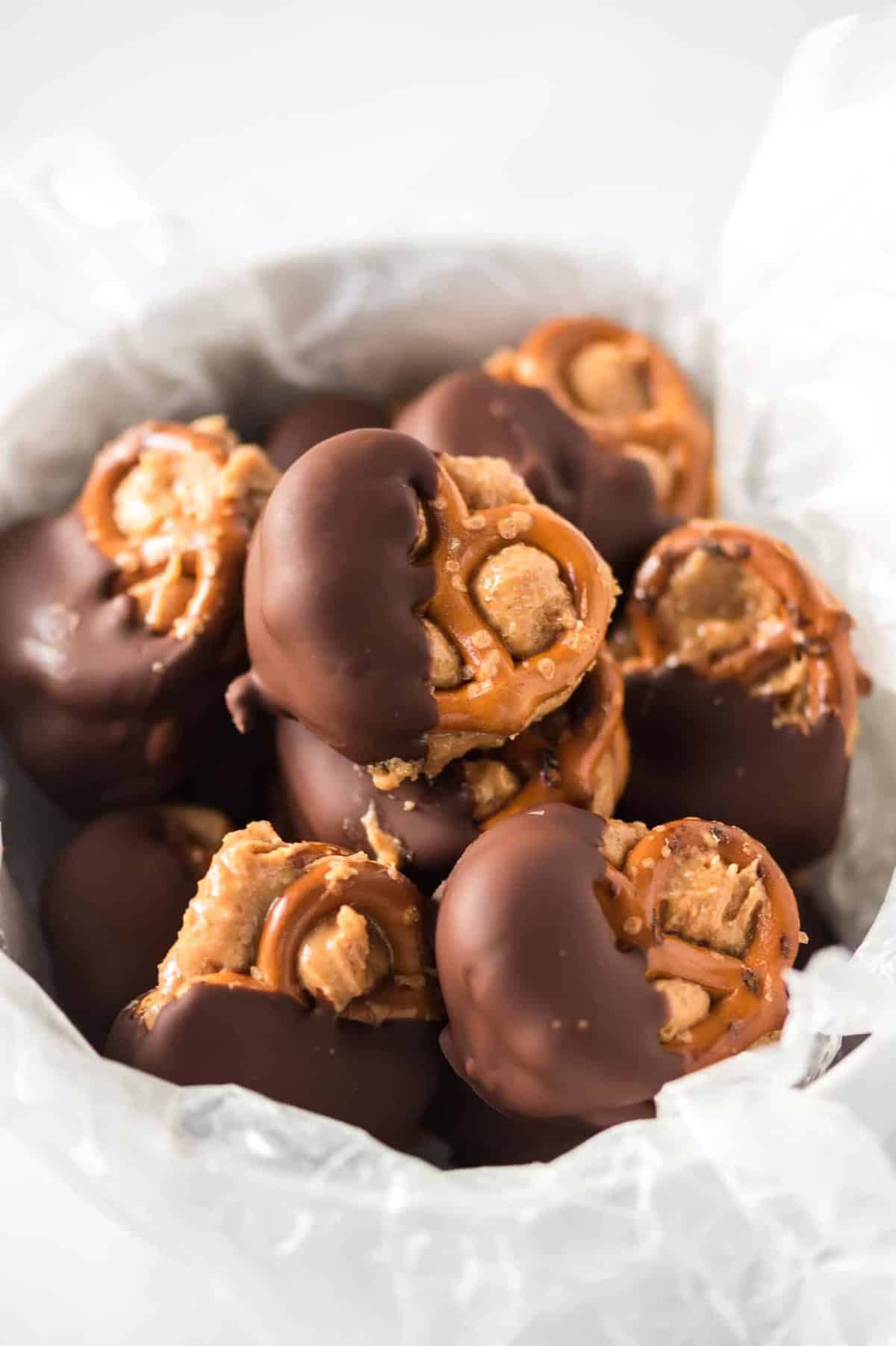 chocolate dipped peanut butter pretzels in a wax paper lined bowl