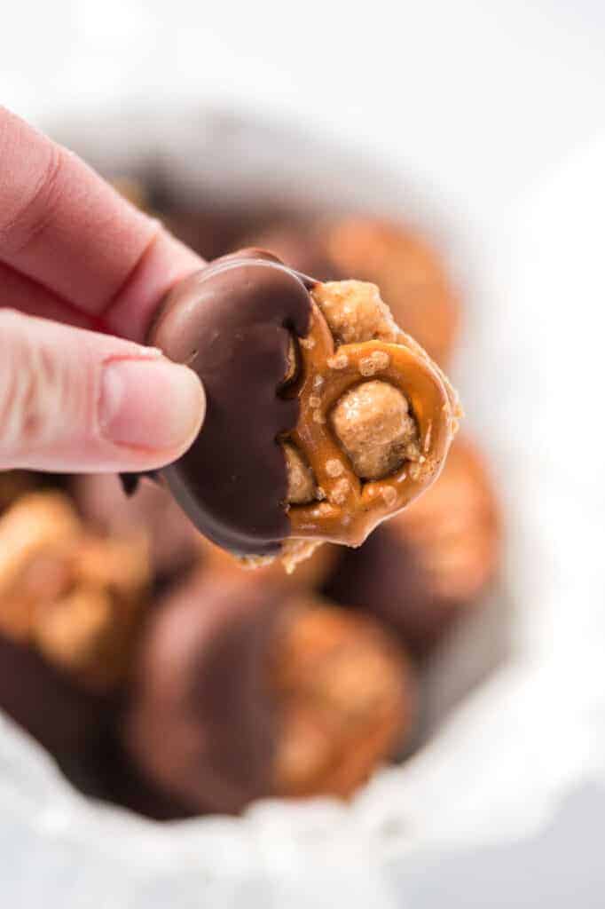 a hand holding a chocolate dipped peanut butter pretzel