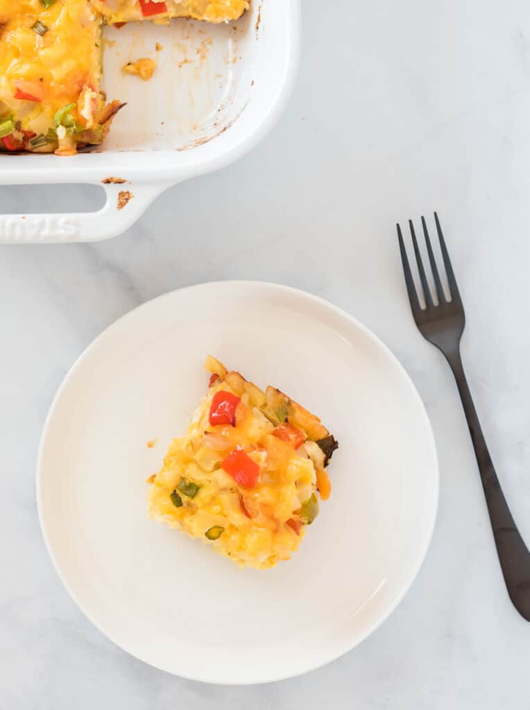a piece of casserole on a white plate with a black fork on the side
