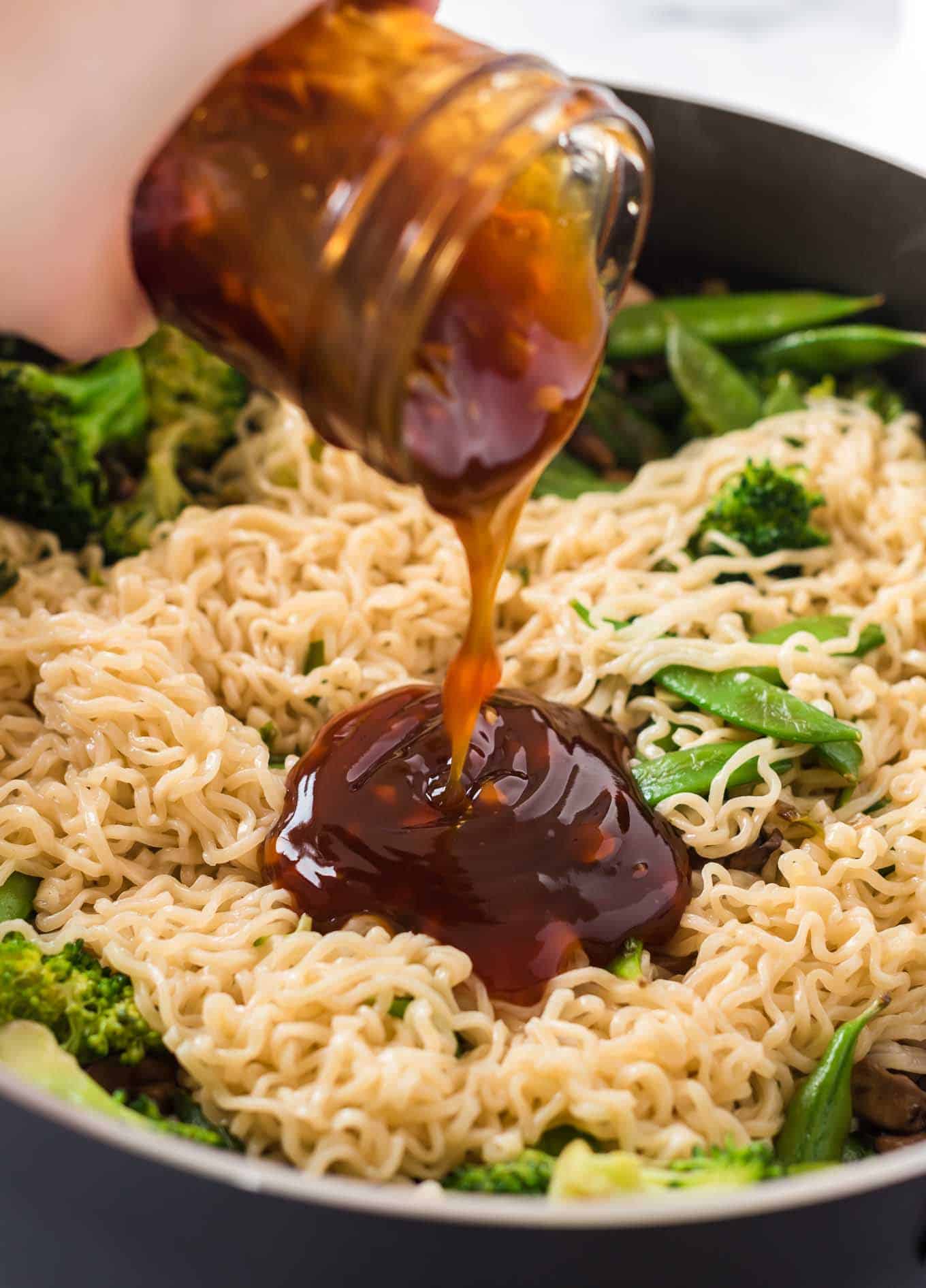 teriyaki sauce being poured onto ramen noodles