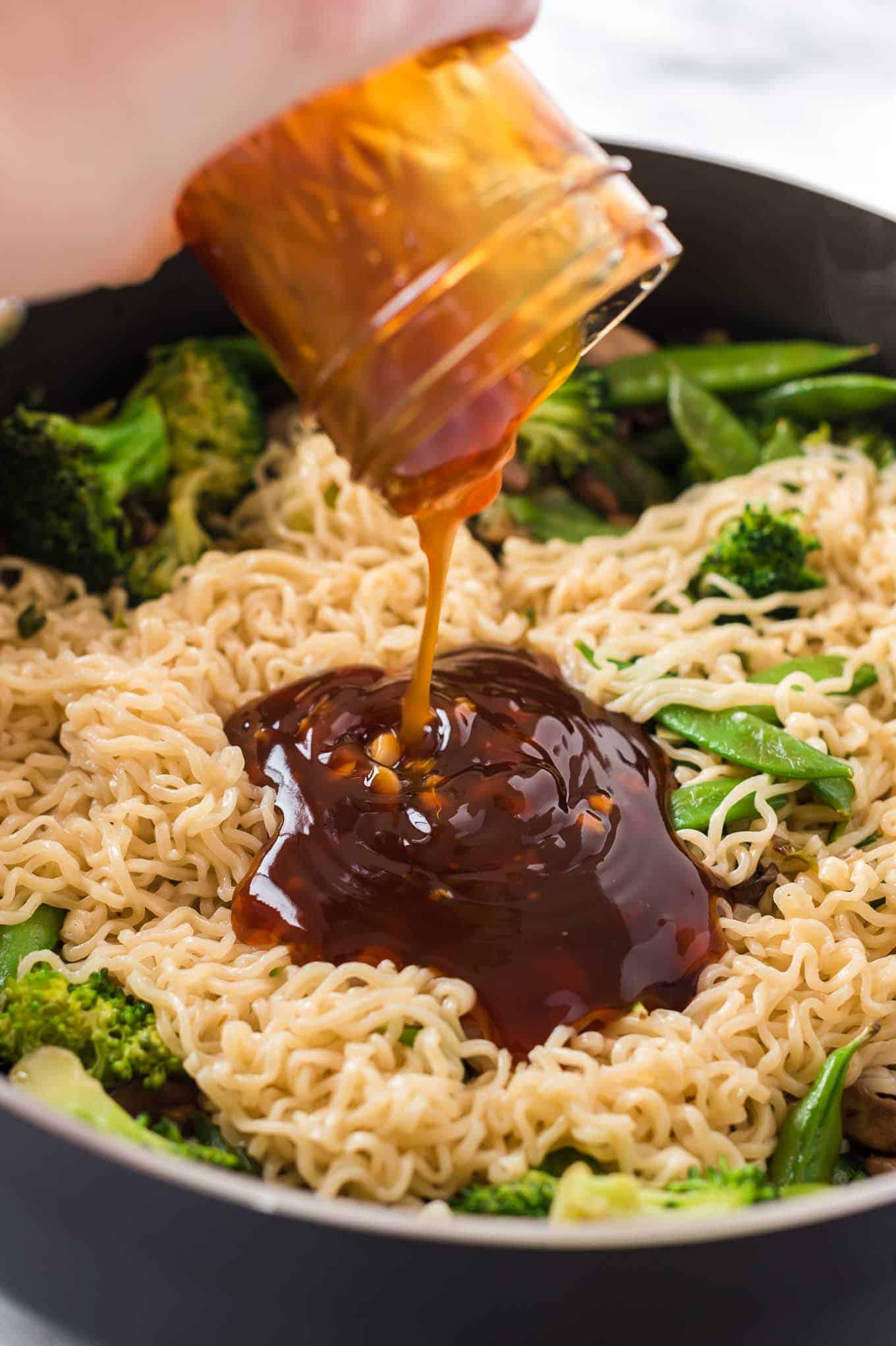 teriyaki sauce being poured onto ramen noodles