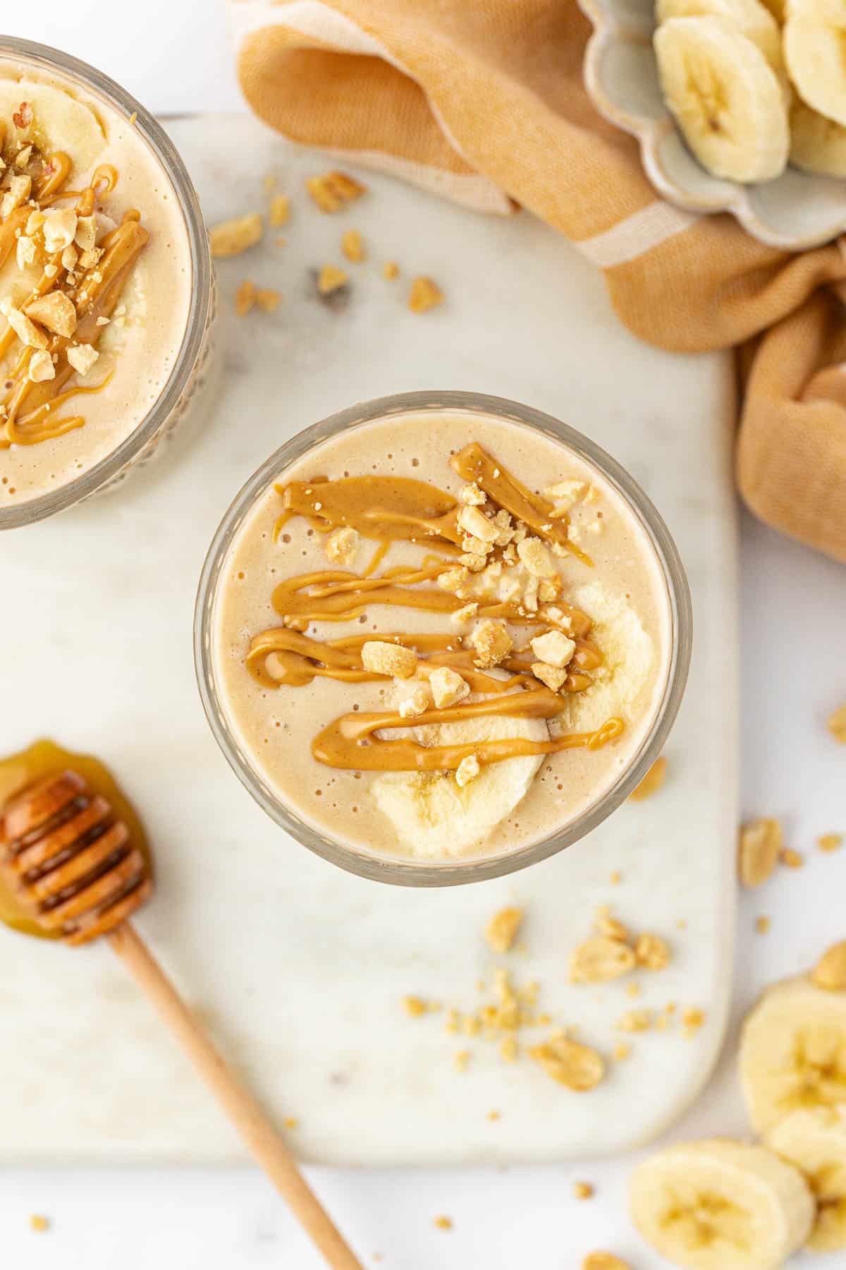 peanut butter banana smoothie topped with drizzled peanut butter and peanuts