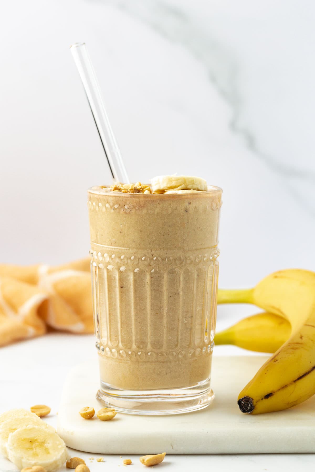 peanut butter banana smoothie in a glass with a straw