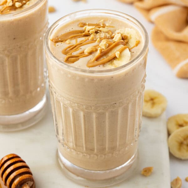 peanut butter banana smoothie topped with drizzled peanut butter and peanuts