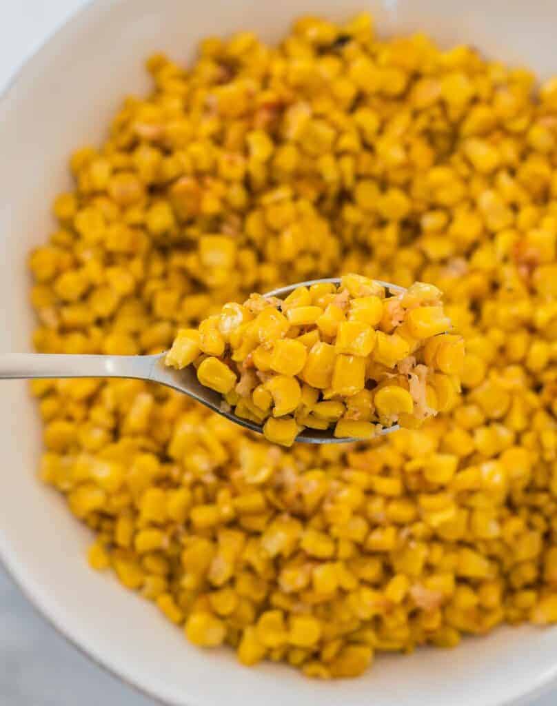 a spoon scooping corn from a bowl