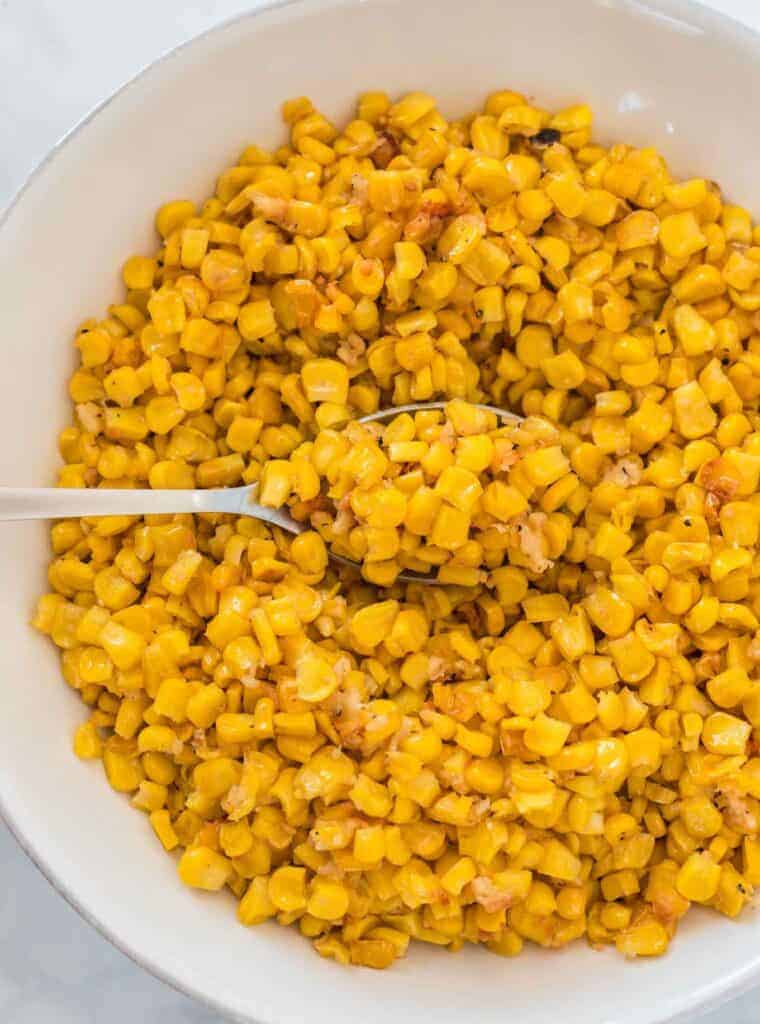 a spoon scooping corn from a bowl