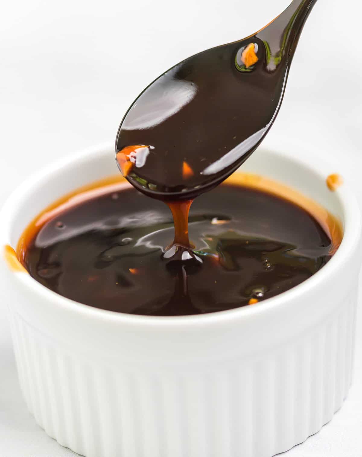 spoon dripping teriyaki sauce over a ramekin