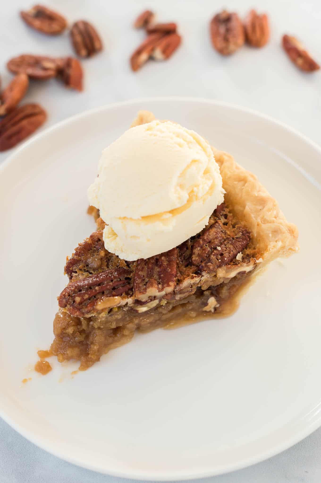 pecan pie without corn syrup on a white plate with a scoop of ice cream on top