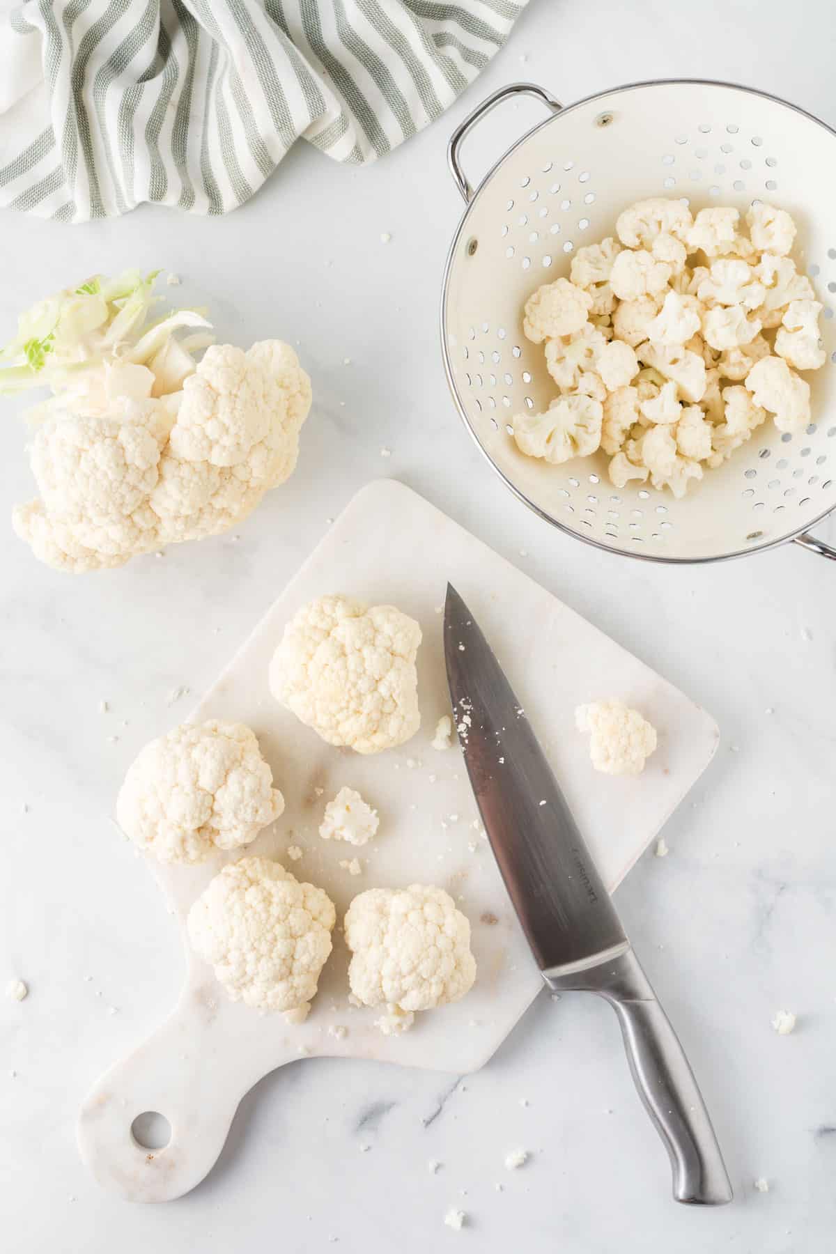 cutting board with cauliflower being cut with a knife