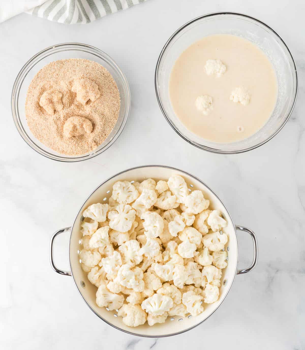 cauliflower being dipped in batter and breading