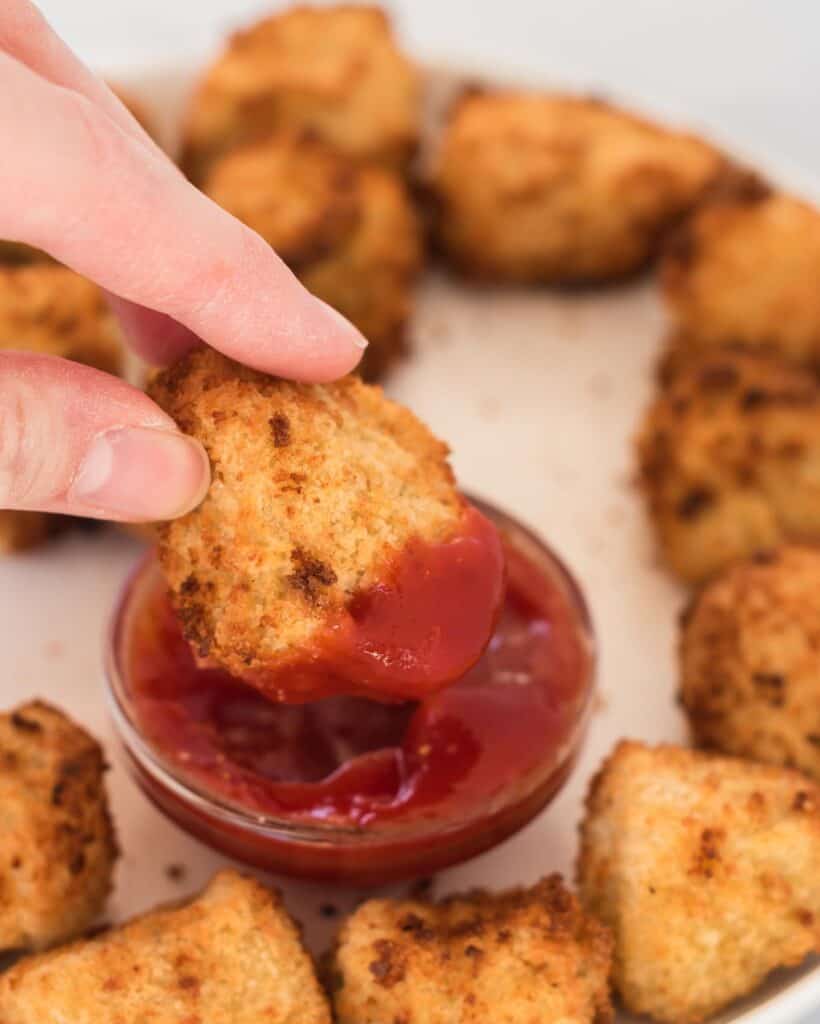 air fryer tofu nugget being dipped into ketchup